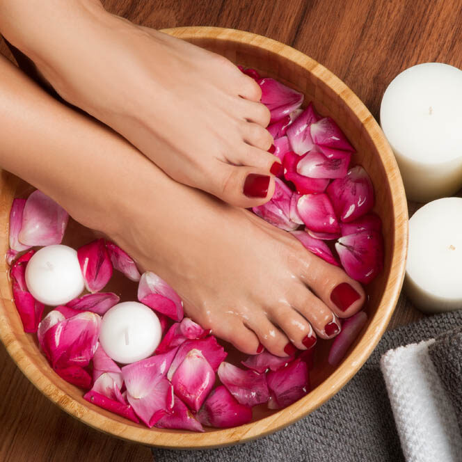 Closeup photo of a female feet at spa salon on pedicure procedure. Female legs in water decoration the flowers.